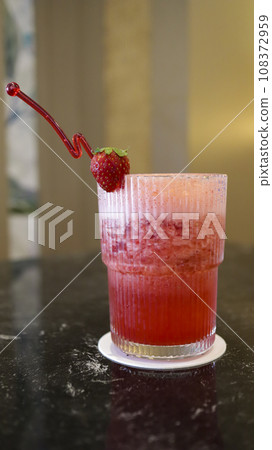 A glass of strawberry juice at the table with a fancy straw. A glass of strawberry juice at the table with a fancy straw. 108372959