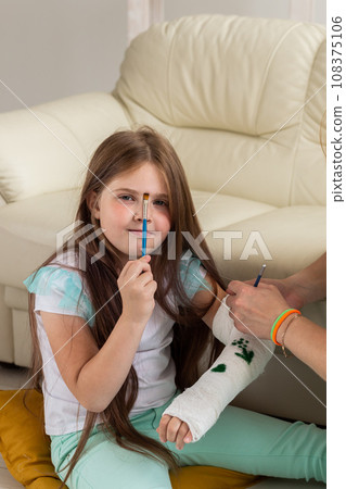 Broken arm a child. Mom and daughter paint on bandage Broken arm a child. Mom and daughter paint on bandage 108375106