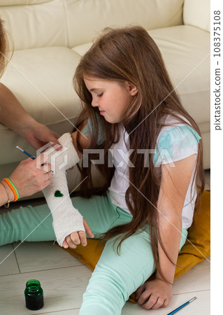 Broken arm a child. Mom and daughter paint on bandage Broken arm a child. Mom and daughter paint on bandage 108375108