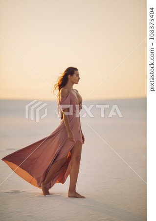 Walking in Desert Fashionable Woman Model in Evening Pink Dress  108375404