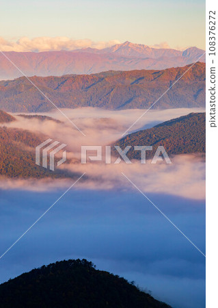 A sea of clouds illuminated by the morning sun and mountains covered in autumn leaves A sea of clouds illuminated by the morning sun and mountains covered in autumn leaves 108376272