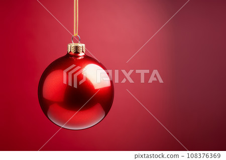 A red Christmas ball on a red background.  108376369