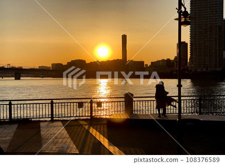 一位母親在夕陽的背景下抱著她的孩子 一位母親在夕陽的背景下抱著她的孩子 108376589
