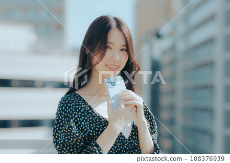 一名年輕女子拿著智慧型手機的場景 一名年輕女子拿著智慧型手機的場景 108376939