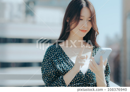 一名年輕女子拿著智慧型手機的場景 一名年輕女子拿著智慧型手機的場景 108376940