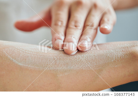 Young man applying cream on his arm Young man applying cream on his arm 108377143