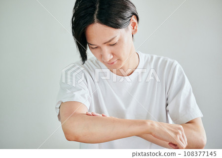 Young man applying cream on his arm Young man applying cream on his arm 108377145