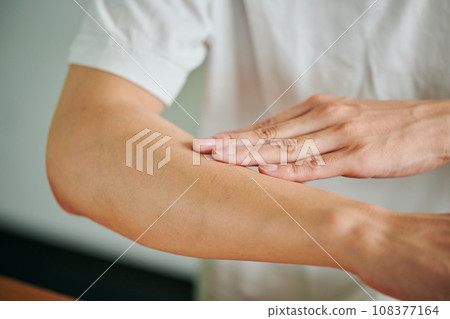 Young man applying cream on his arm 108377164