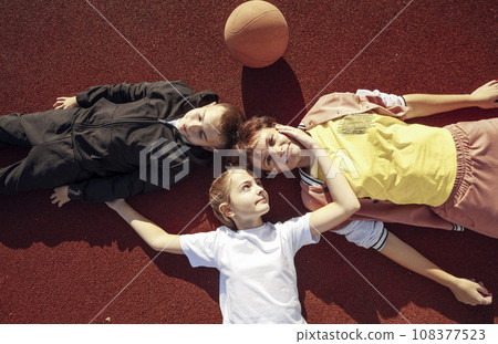 Laid-back Laughter: Unwinding with Children on the Basketball Court Surface with mother 108377523