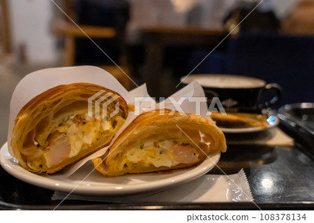 Croissant sandwich eaten at a cafe 108378134