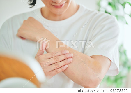 Young man applying cream on his arm 108378221