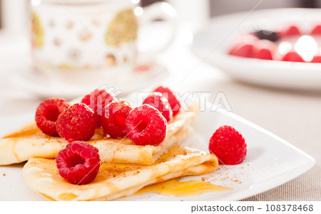 Breakfast of pancakes with fresh raspberries on table 108378468