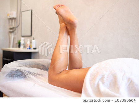 The hands of the masseur massage the legs of woman in the spa. 108380604