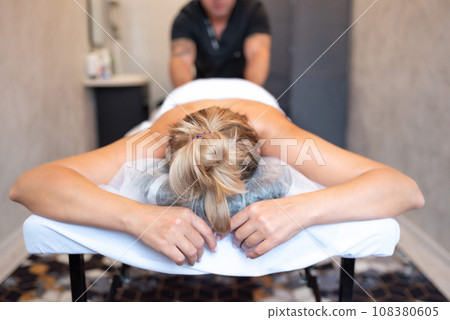 male masseur massages the back and shoulder blades of woman lying on massage table 108380605