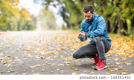 A good-looking athlete puts on his sports watch before running. A good-looking athlete puts on his sports watch before running. 108381492