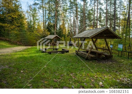A place prepared for lighting a bonfire in a natural outdoor area in Estonia. Firewood next to metal fireplace with fire and boiler. Estonia, Europe 108382151