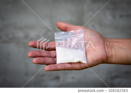 A bag of white powder in hand. Image for prohibited substances, addiction concept A bag of white powder in hand. Image for prohibited substances, addiction concept 108382563