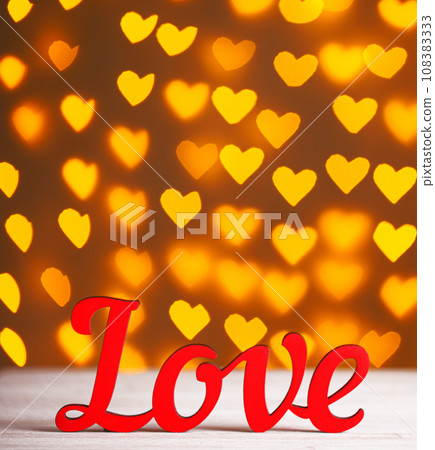 the inscription Love on a wooden background with beautiful hearts made of lights on a blurred background the inscription Love on a wooden background with beautiful hearts made of lights on a blurred background 108383333