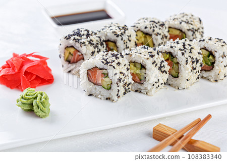 Sushi with salmon on a white plate with wasabi, ginger, soy, chopsticks on a white background Sushi with salmon on a white plate with wasabi, ginger, soy, chopsticks on a white background 108383340