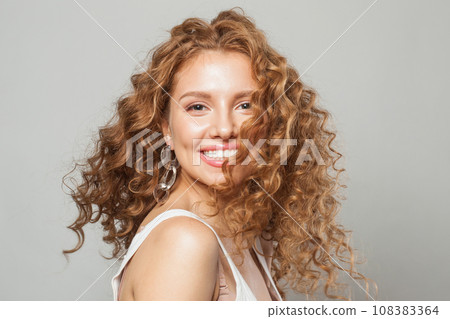Cheerful happy woman with long natural healthy brown curly hair and cute smile looking at camera  108383364