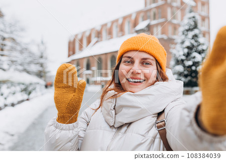 Stylish happy woman tourist making selfie photo in front of the famous St. Mary's Basilica on the Market square. Travel concept and discovery of beautiful places. Krakow, Poland 108384039