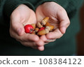 Hands with acorns and rose hips on blurred background, closeup 108384122