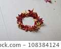 wreath made of red and yellow leaves on a grey paper background 108384124