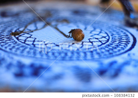 Handmade women's jewelry pendant in the shape of an acorn lies on an embroidered napkin Handmade women's jewelry pendant in the shape of an acorn lies on an embroidered napkin 108384132