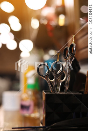Professional hairdressing tools. Various steel scissors and combs, hairbrushes on wooden table on barbers workplace at barbershop salon. The concept of the hairdressing beauty industry. Copy space 108384481