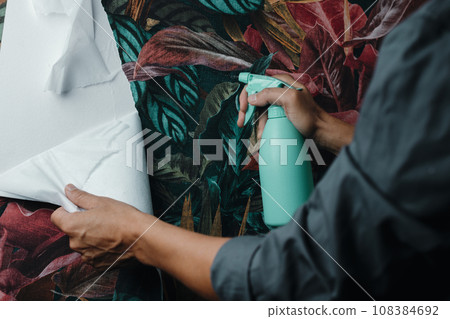 wets the wallpaper to remove it from the wall 108384692