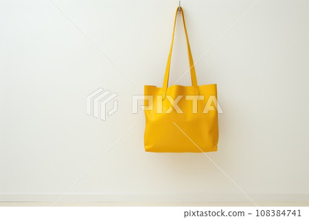 Yellow paper shopping bag hanging on white wall 108384741
