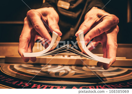 Dealer or croupier shuffles poker cards in a casino on the background of a table, chips. Concept of poker game, game business. Playing for money, a big win, a jackpot, gambling, a desire to get rich. Dealer or croupier shuffles poker cards in a casino on the background of a table, chips. Concept of poker game, game business. Playing for money, a big win, a jackpot, gambling, a desire to get rich. 108385069