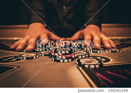 Dealer or croupier shuffles poker cards in a casino on the background of a table, chips. Concept of poker game, game business. Playing for money, a big win, a jackpot, gambling, a desire to get rich. 108385109