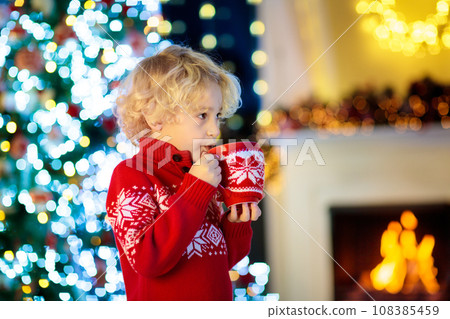 Kids at Christmas tree. Children drink hot cocoa. 108385459