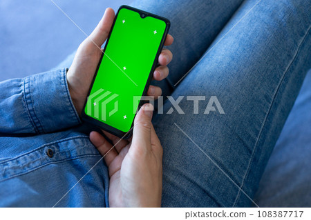 a person holding a phone with a green screen, is holding a smartphone a person holding a phone with a green screen, is holding a smartphone 108387717