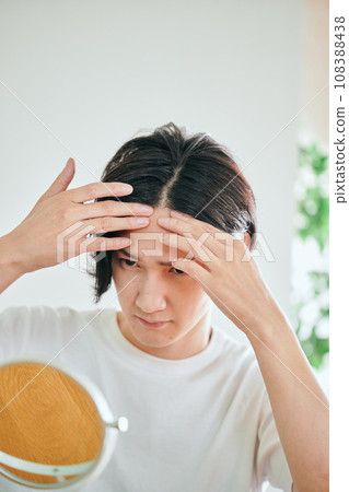 A young man who is concerned about hair loss 108388438