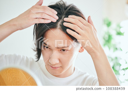 A young man who is concerned about hair loss 108388439