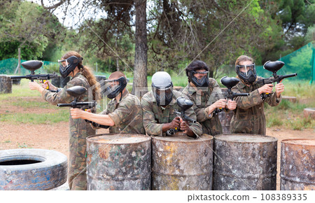Group of paintball players aiming and shooting with guns Group of paintball players aiming and shooting with guns 108389335