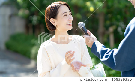 A woman being interviewed on her way home from shopping 108389350