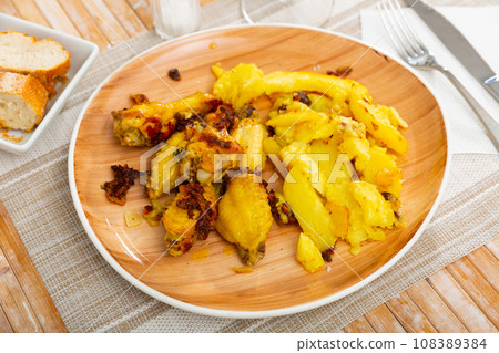 Garlic chicken with potato on plate, served with bread. 108389384