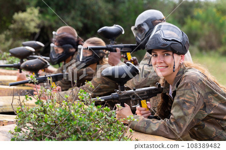 Group of paintball players aiming and shooting with guns 108389482