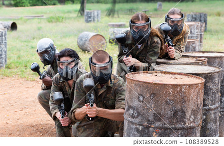 Group of paintball players aiming and shooting with guns 108389528