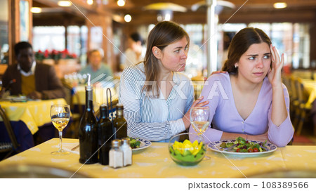 Woman comforting upset female friend during dinner in restaurant 108389566