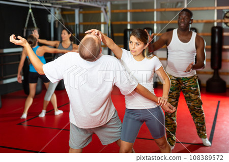 Girl self defense training gym learning to do painful grip Girl self defense training gym learning to do painful grip 108389572