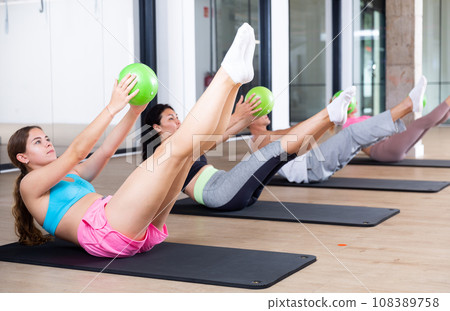 Young adults doing exercises with pilates ball 108389758