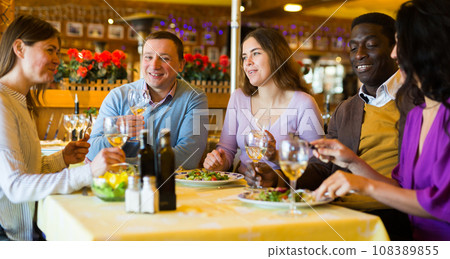 Adult men and women having friendly meeting at dinner in restaurant 108389855