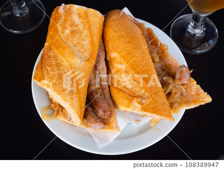 Sandwiches bocadillo from fresh baguette stuffed with fried sausages and onions 108389947