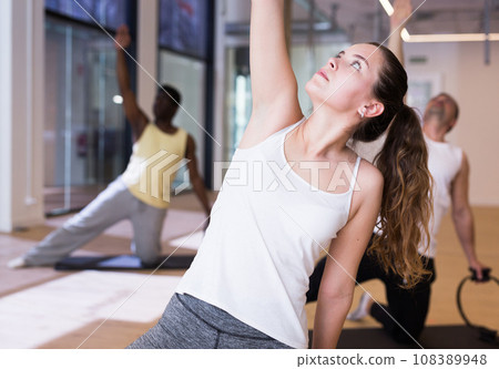 Girl exercising with flexible ring during group pilates class 108389948