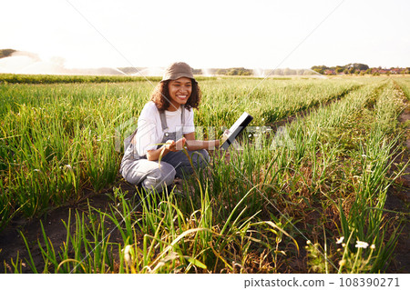 Smiling woman farmer work on digital tablet standing on field. Agricultural business concept Smiling woman farmer work on digital tablet standing on field. Agricultural business concept 108390271