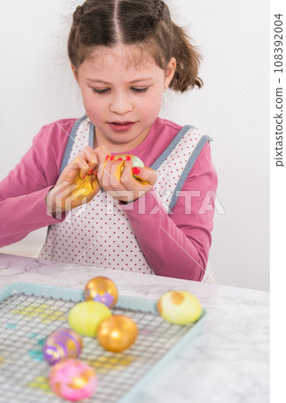 Easter egg coloring. Painting Easter eggs with gold luster. 108392004